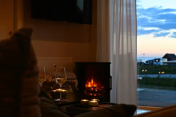 Cozy evening time preparation. Glass of wine, a fireplace, and evening view.