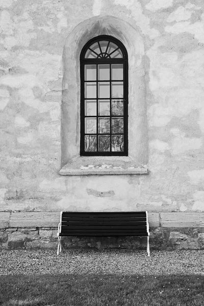 Gothic-style window and a modern bench.