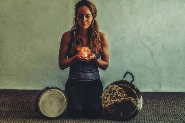 Piękna medytująca kobieta ze świecą lotosową w ręku i djembe. — Zdjęcie stockowe