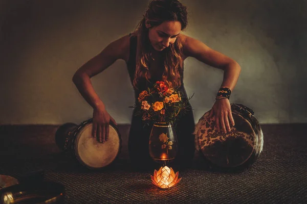 Bela mulher meditando com vela de lótus em sua mão e djembe. — Fotografia de Stock