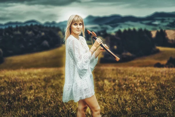 Girl playing on shaman flute in the nature. — Stock Photo, Image