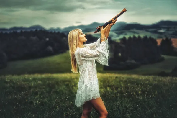 女孩在大自然中吹奏萨满长笛. — 图库照片