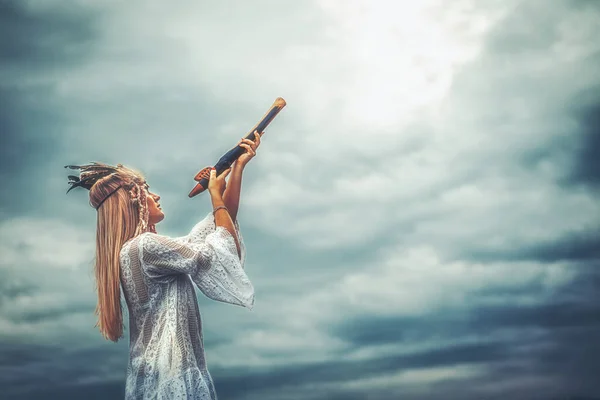 Mooi sjamanistisch meisje spelen op sjamaan fluit in de natuur. — Stockfoto