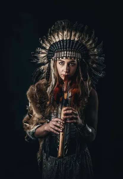 Beautiful shamanic girl playing on shaman flute in the studio. — Stock Photo, Image