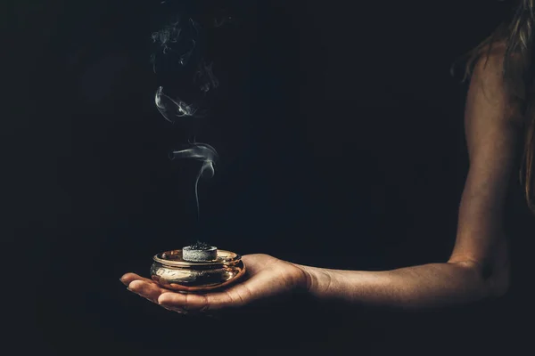 Incenso na mão de uma mulher, fumaça de incenso em um fundo preto. — Fotografia de Stock