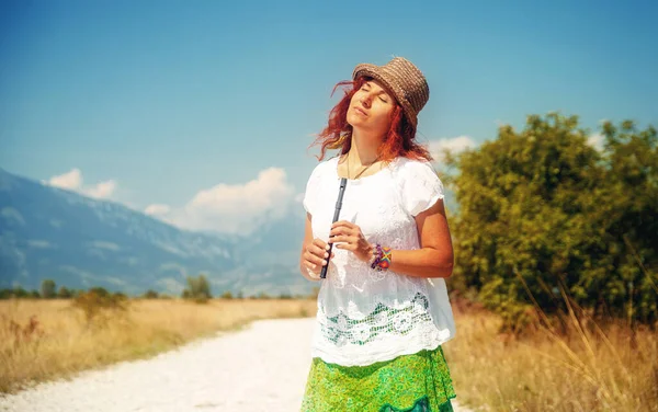Mulher com uma flauta de pé na estrada. — Fotografia de Stock