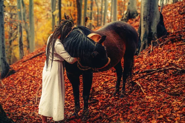 Shaman woman in autumn landscape with her horse. — 图库照片