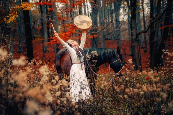 Shaman woman in autumn landscape with her horse. — Fotografia de Stock