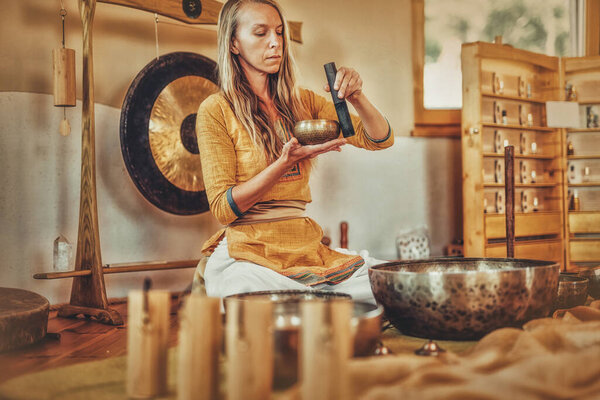 beautiful woman playng on tibetan bowl, ceremonial space