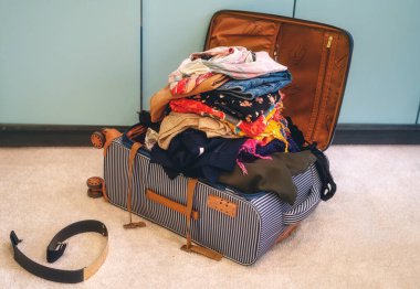 Odada giysilerle dolu bir bavul aç.