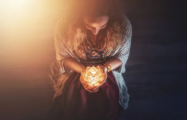 beautiful meditating woman with lotus candle in her hand