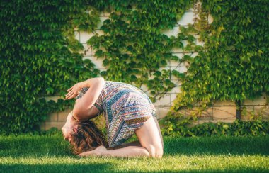 Güzel bir kadın bahçede yoga yapıyor.