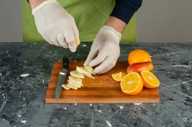 Eldivenli bir erkek, tahtanın tepesindeki elmalara limon suyu sıkıyor. 