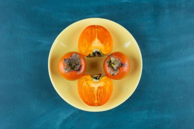 Sarı bir tabağa yerleştirilmiş tam ve dilimlenmiş hurma meyvesi. Yüksek kalite fotoğraf