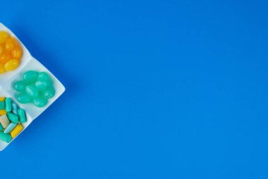 Beyaz tabak dolusu sert şeker ve mavi yüzeyi çiğneyen diş etleri. 