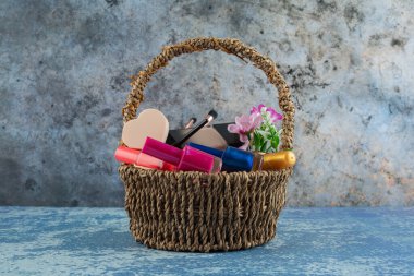 Mermer yüzeyde dekoratif kozmetiklerle dolu hasır sepet.