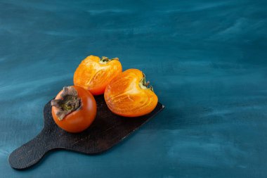 Siyah kesim tahtasında tam ve yarım dilimlenmiş hurma meyveleri.. 