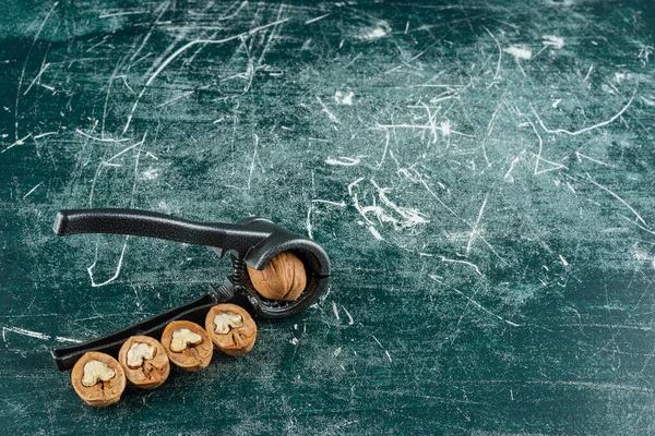 Ceviz kırma aracı mermer arka planda kabuklu ceviz 