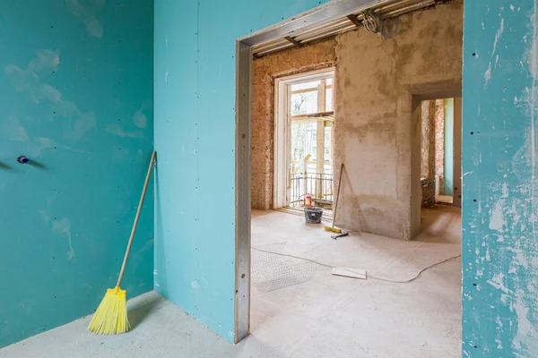 緑の石膏ボードや乾燥壁やアパート内のほこりやゴミ収集のための黄色のほうきは、建設、改造、改修、拡張、修復と再建中です。 — ストック写真