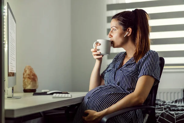 Gravid Kvinna Dricker Kaffe Framför Dator Med Hörlurar Öronen Kvinna — Stockfoto