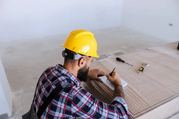 Een Achteraanzicht Van Bebaarde Timmerman Hurken Nieuw Appartement Het Berekenen — Stockfoto