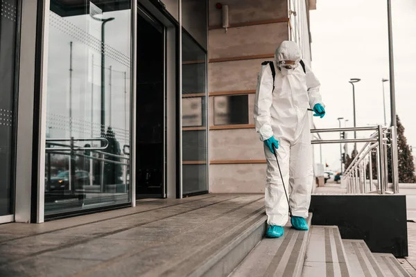 一名身穿白色防护服和面罩的男子用化学品消毒前门和通往办公大楼的楼梯 Covid 19预防 大流行病 — 图库照片