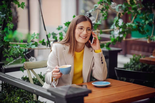 Sarı Kazaklı Gülümseyen Genç Bir Kadın Kafeteryanın Terasında Oturuyor Elinde — Stok fotoğraf