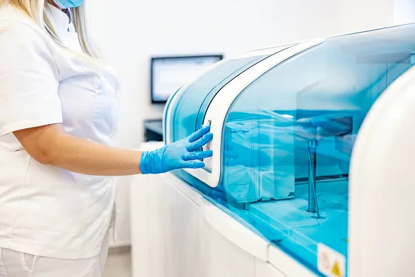 实验室里的现代机器护士站在机器旁边对血液进行取样和分析的护士检测疾病和病毒 微生物学 — 图库照片