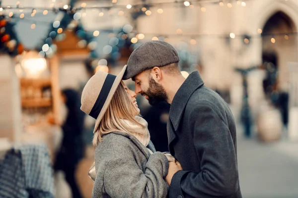 クリスマスのカップルはクリスマスに屋外でロマンチックな瞬間を持っています 若いカップルが通りに立って手を握って新年にエスキモーのキスをする — ストック写真