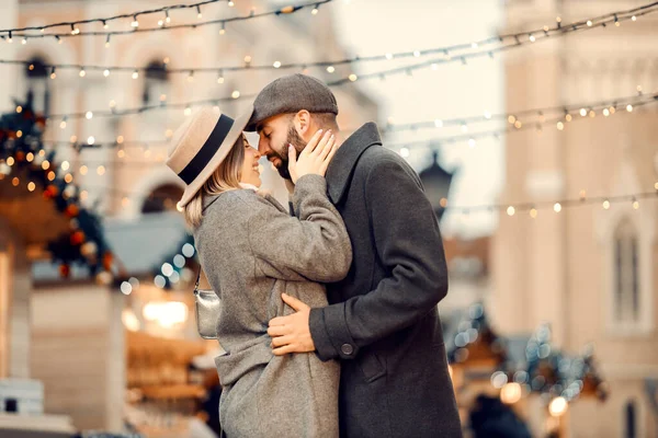 クリスマスの人々は新年に通りでキスをする 若い幸せなカップルが路上に立っていて 新年に抱き合ってキスをしています — ストック写真