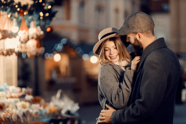 クリスマスの前夜に路上で抱き合っているカップル クリスマスに通りに立つ若い幸せなカップル 抱き合って愛を分かち合う — ストック写真