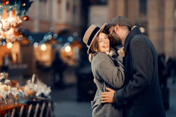 クリスマス愛好家は大晦日に屋外でキスをします 幸せな若い男が路上に立って頬にキスしクリスマスの前夜に彼のガールフレンドを抱きしめる — ストック写真