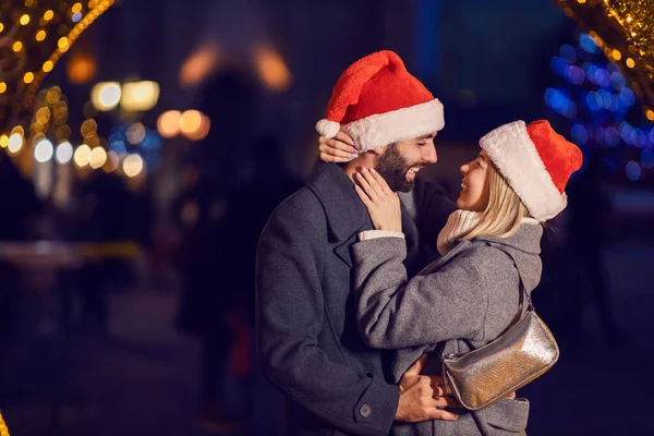 Noel Arifesinde Dışarıda Kucaklaşan Noel Çifti Noel Baba Şapkalarına Aşık — Stok fotoğraf