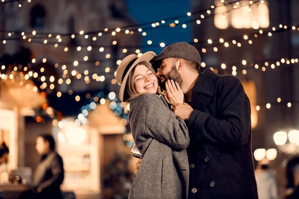 新年の夫婦は大晦日に通りでキスをします 新年の前夜に路上で立っている愛の若いカップル 抱擁とキス — ストック写真