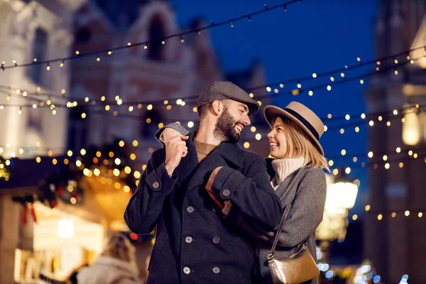 大晦日に屋外で抱擁クリスマスカップルを愛情 クリスマスの前夜に路上に立っている幸せな愛情のあるカップルは 抱き合ってお互いを見て — ストック写真