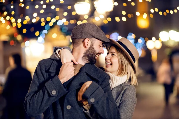 クリスマスに路上で抱きつく愛の恐ろしいクリスマスカップル クリスマス イブの通りに立って抱き合ってお互いを見てる — ストック写真