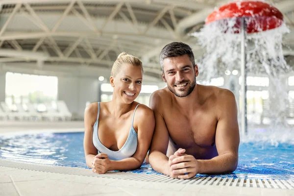 笑顔のカップルは 温水と泡立ちの良い水とリラックスしたプールに立っています 二人はカメラを見ている スパセンターでの一日 — ストック写真