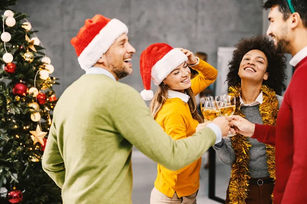 会社での新年のパーティー クリスマスツリーの隣に立ち 大晦日にシャンパングラスで乾杯する多文化の仲間たち — ストック写真