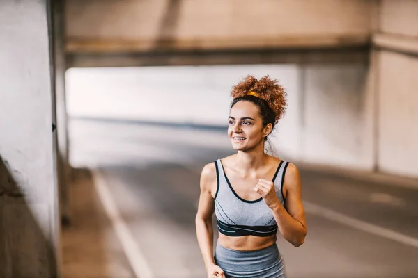 A happy urban runner with healthy habits running on the road with minimum effort and enjoying sports activity. An urban runner running in the city.