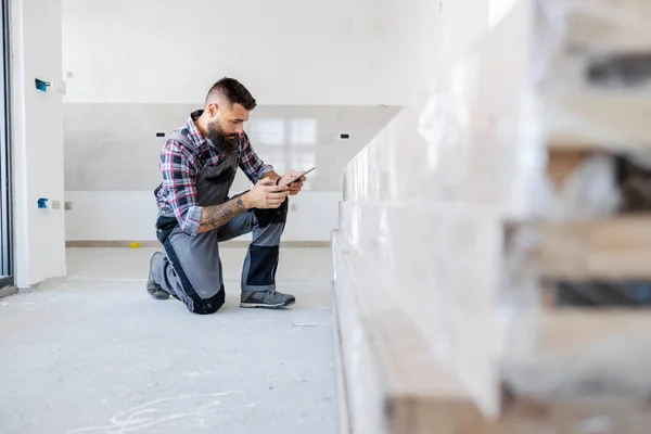 Innovative Supervisor Overalls Kneeling New Building Checking Materials His Tablet — Stockfoto