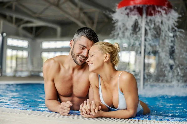 愛のカップルは スパやウェルネスセンターで温水と泡のあるプールで抱き合っています スパセンターでロマンチックな週末 — ストック写真