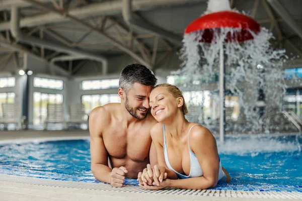 リゾートでは プールで泡立ちと温水でかわいい成熟したカップルが抱き合っています ウェルネスセンターでロマンチックなカップル — ストック写真