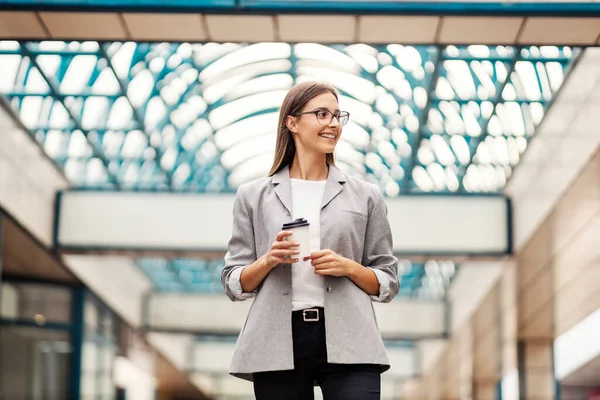 ビジネスの若い女性とコーヒーに行く ビジネスの前に立ち笑顔で横を見ながらコーヒーを手に取り — ストック写真