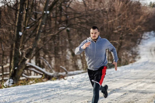 눈내리는 겨울날 숲에서 빠르게 달리는 스포츠맨 — 스톡 사진