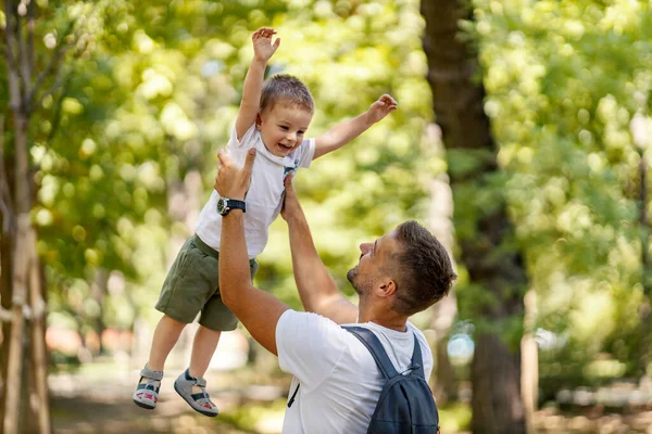 Freedom, free family activities on weekends. A family in the woods spends time together. The adult man throws the boy above his head and the boy laughed excitedly and rejoices