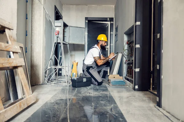 Ένας Έμπειρος Εργάτης Γονατίζει Στην Αίθουσα Του Κτιρίου Κατά Διαδικασία — Φωτογραφία Αρχείου