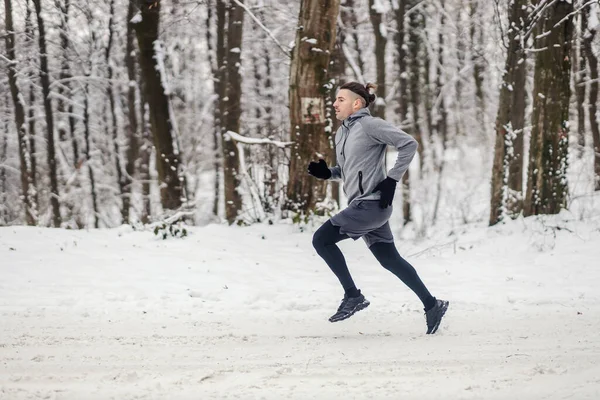 눈내리는 겨울날 속에서 빠르게 달리는 스포츠맨 — 스톡 사진