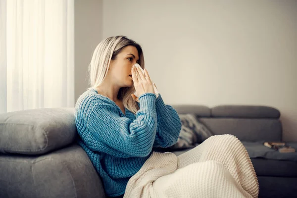 一个生病的女人坐在家里吹鼻涕 — 图库照片