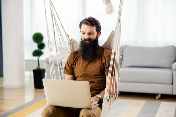 Homem Barbudo Sentado Casa Balançar Sua Casa Aconchegante Usando Laptop — Fotografia de Stock