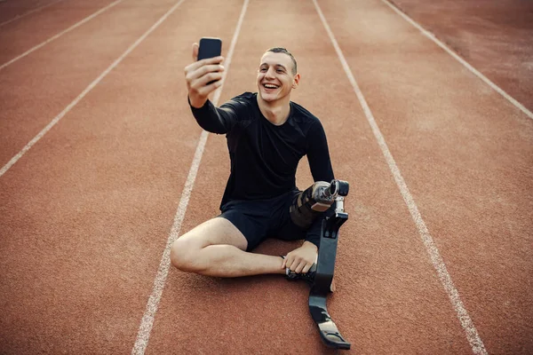 Takma Bacaklı Mutlu Bir Engelli Koşucu Koşu Pistinde Oturup Selfie — Stok fotoğraf